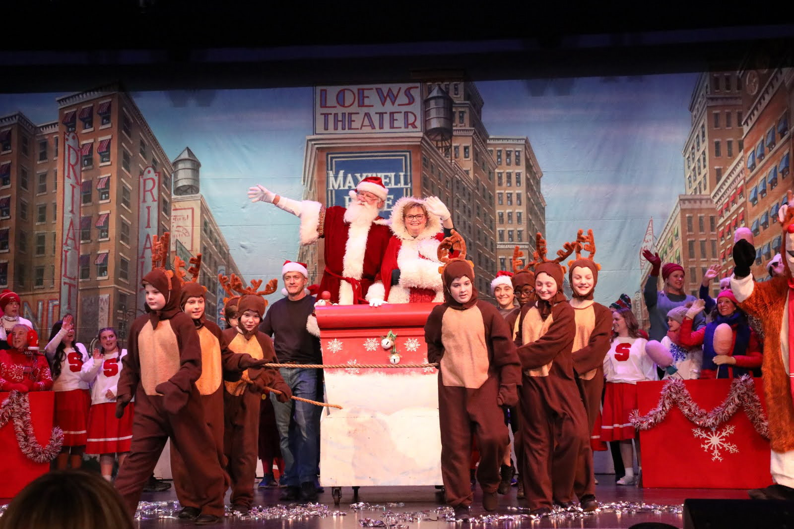 Santa and Mrs. Claus wave from the sleigh in a Christmas parade scene.